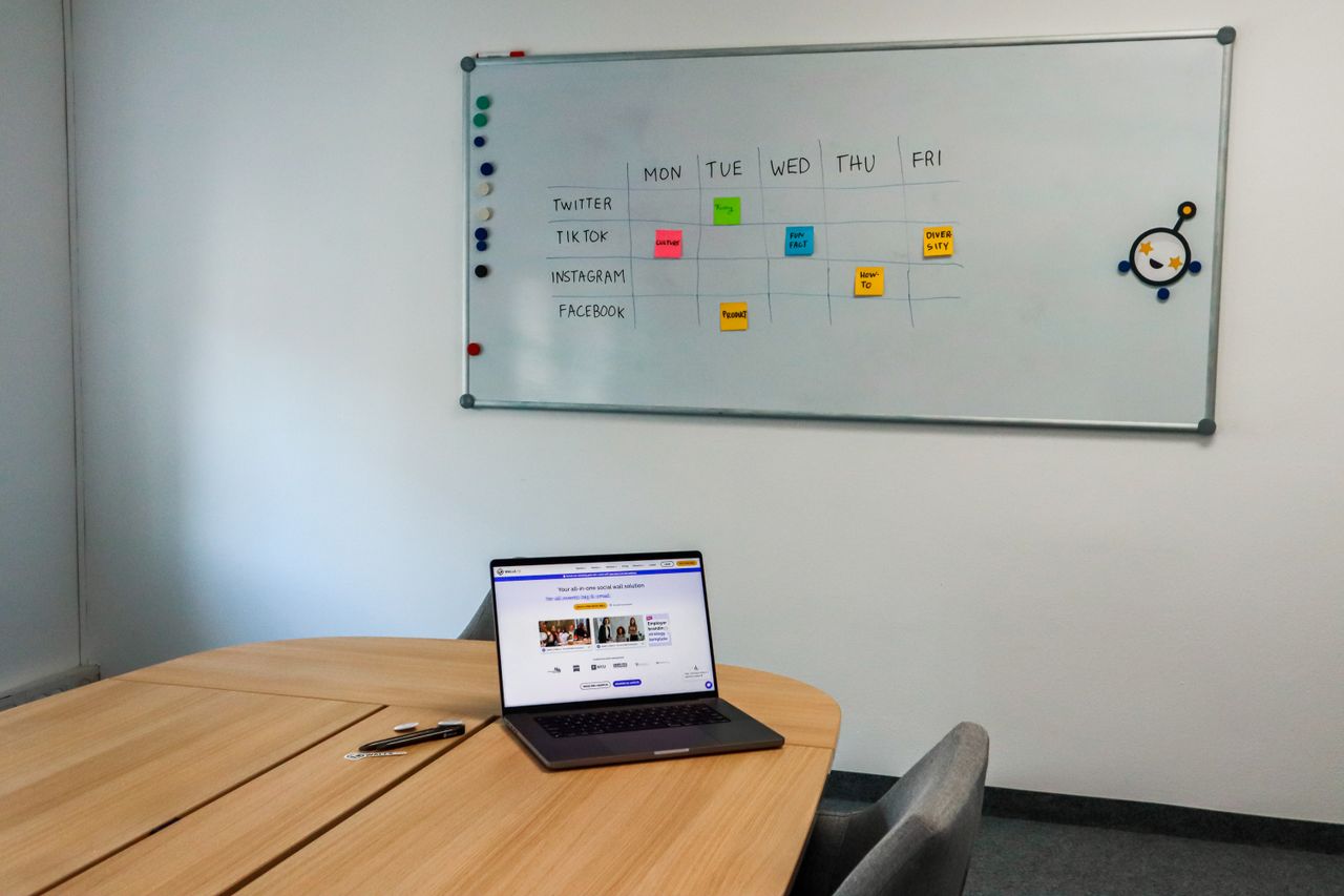 journey Office setup featuring a conference table, laptop, and organized whiteboard schedule, highlighting a tech-driven workspace.